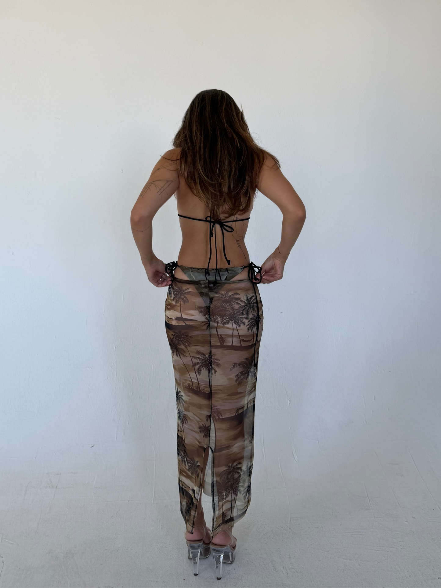Woman wearing a palm tree pattern skirt against a white background